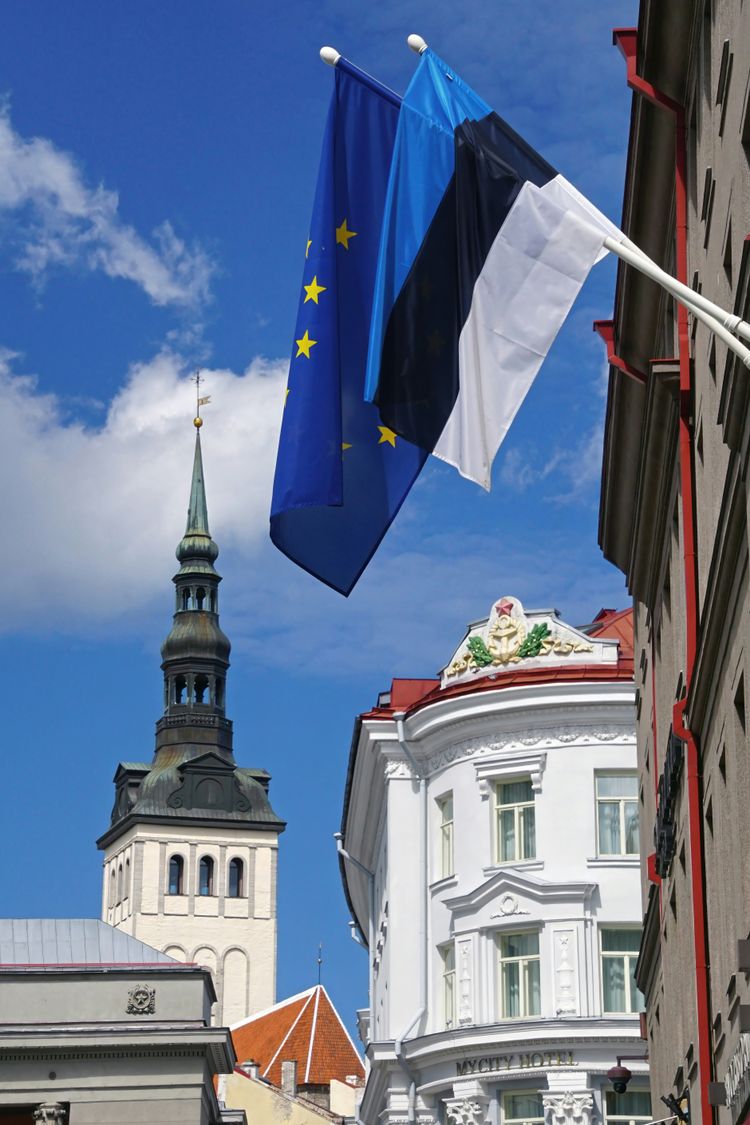 A flag flying in the air next to a tall building