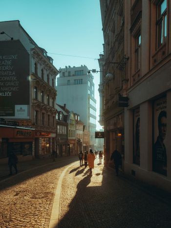 a group of people walking down a street next to tall buildings