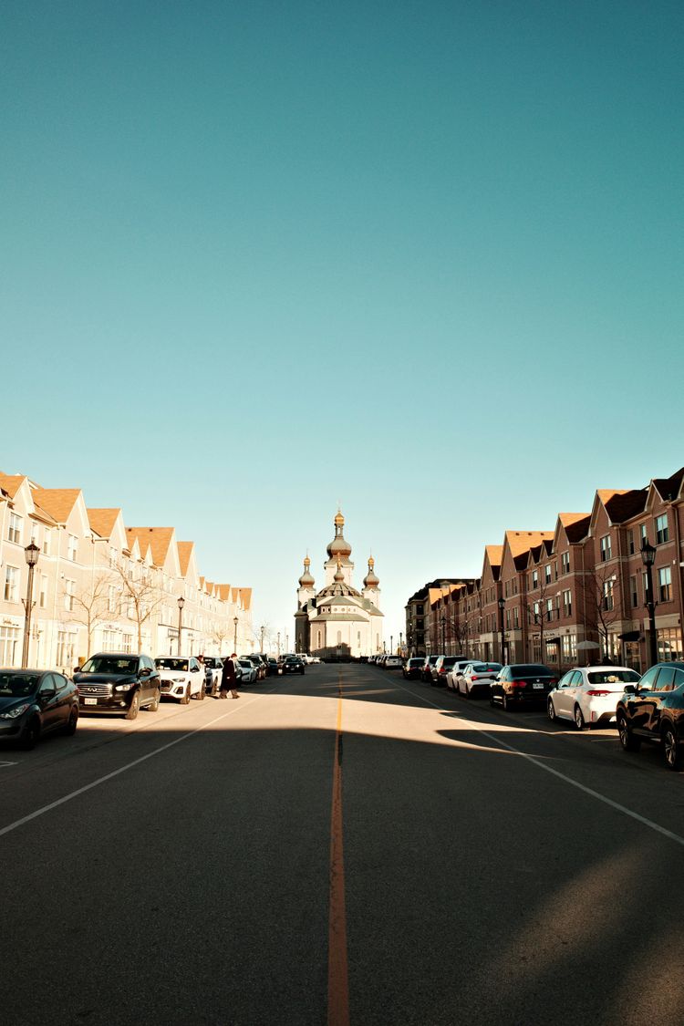 A street lined with parked cars next to tall buildings