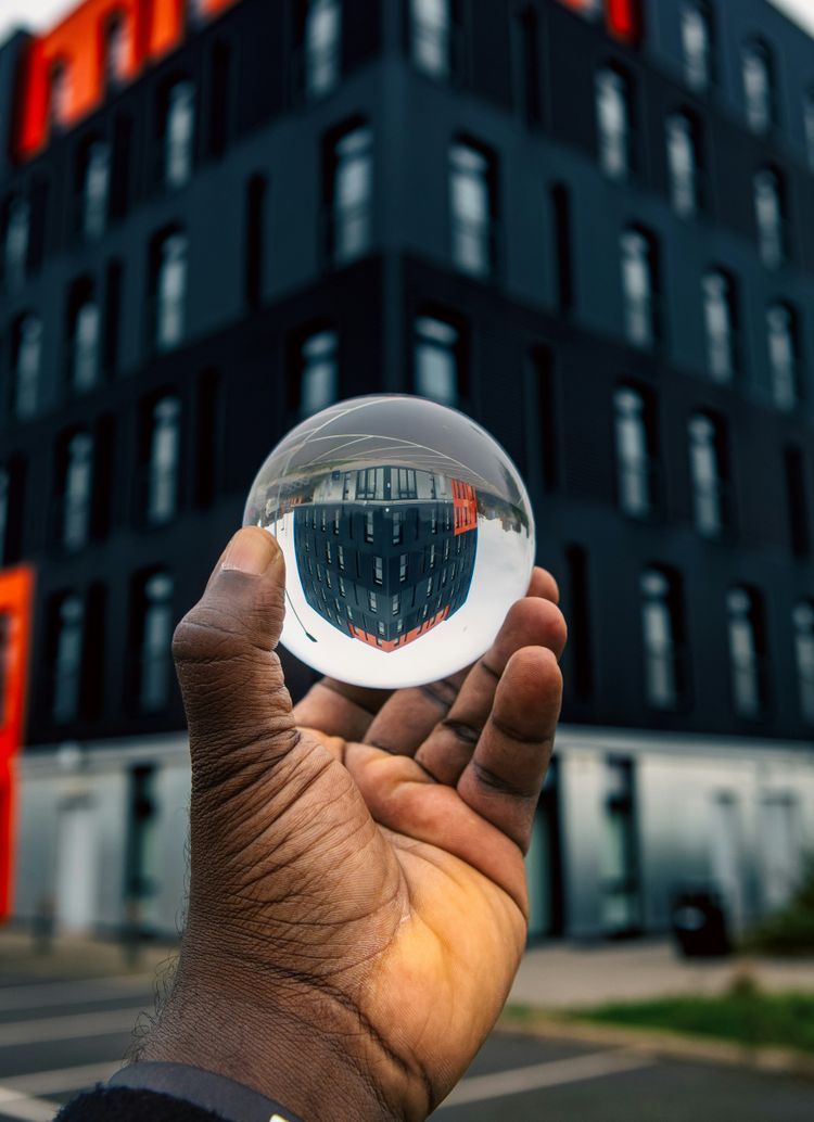A hand holding a glass ball in front of a building