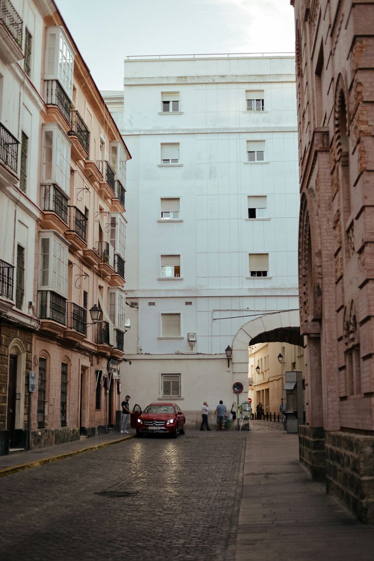 red car parked beside white concrete building during daytime