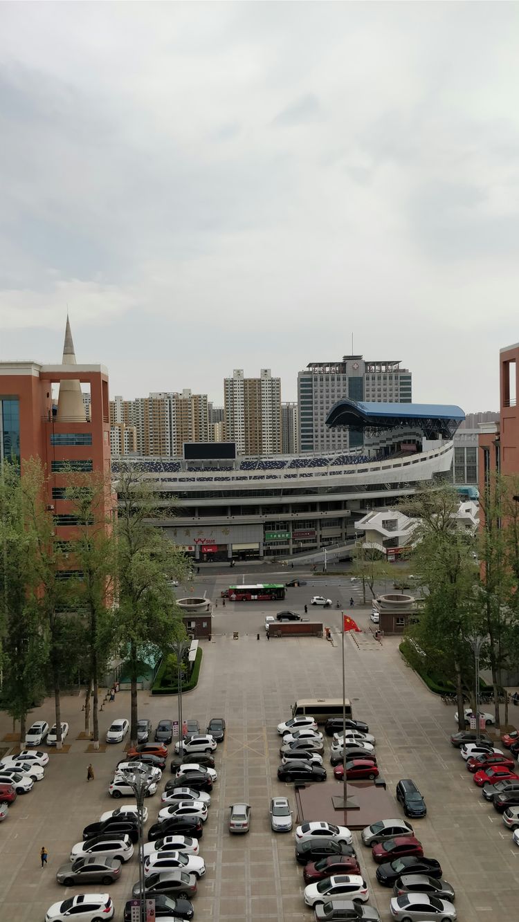 cars parked on parking lot near high rise buildings during daytime