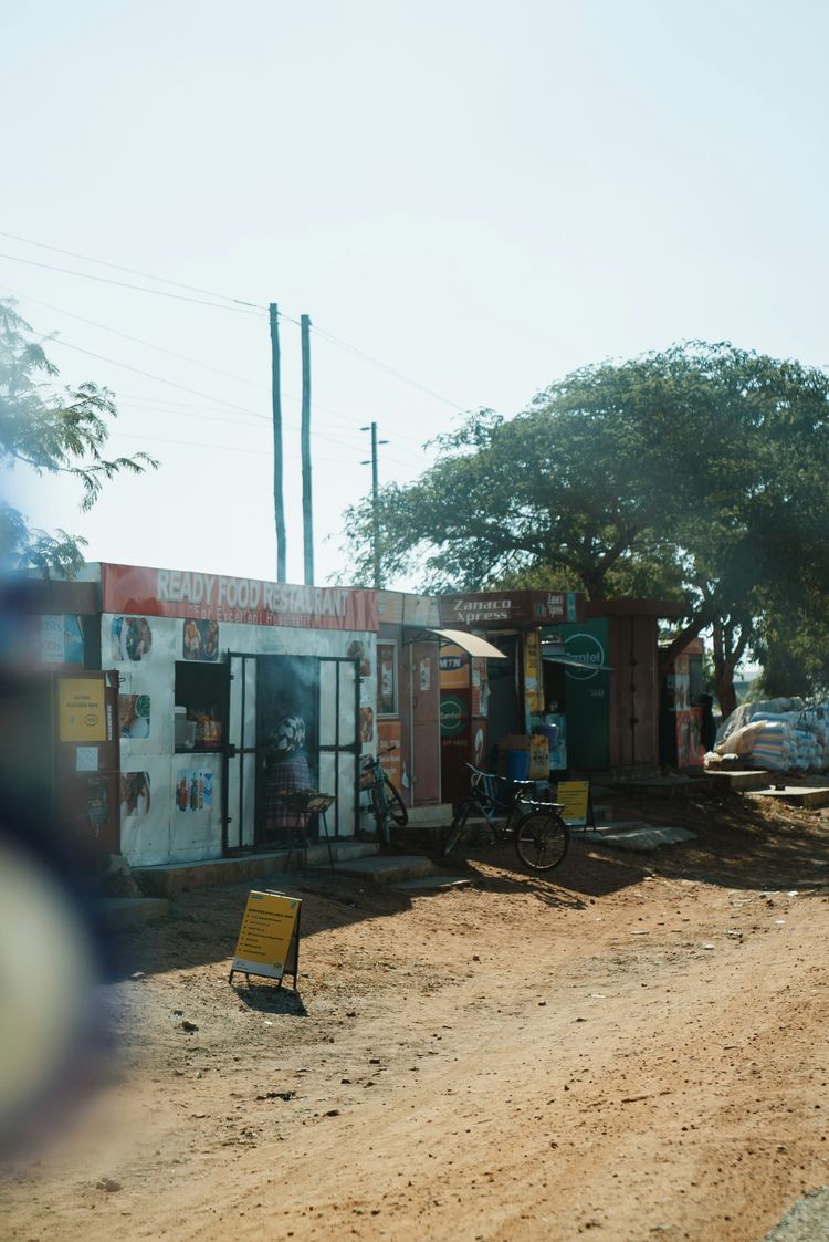 a dirt road next to a small store