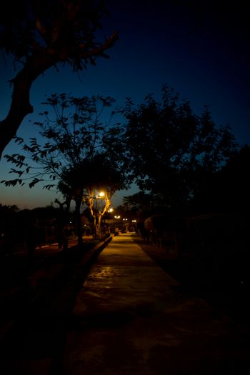 a dark street at night with a street light in the distance