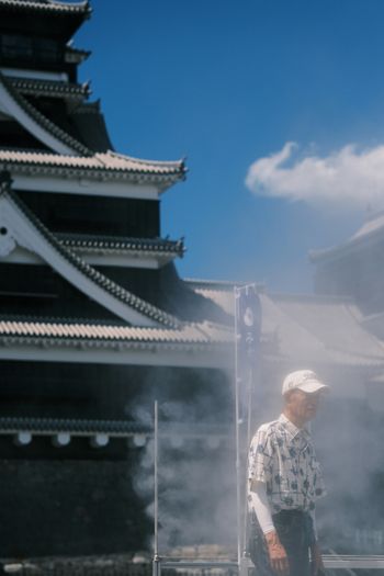 A man standing in front of a building with steam coming out of it