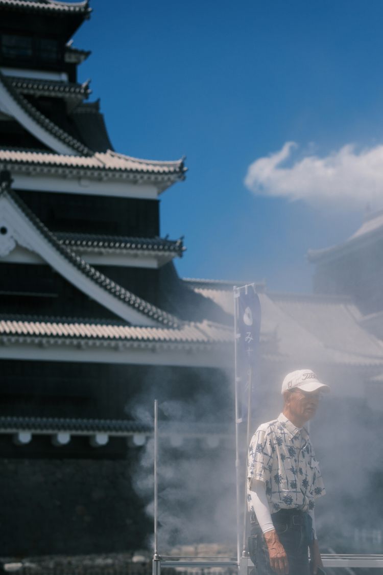 A man standing in front of a building with steam coming out of it