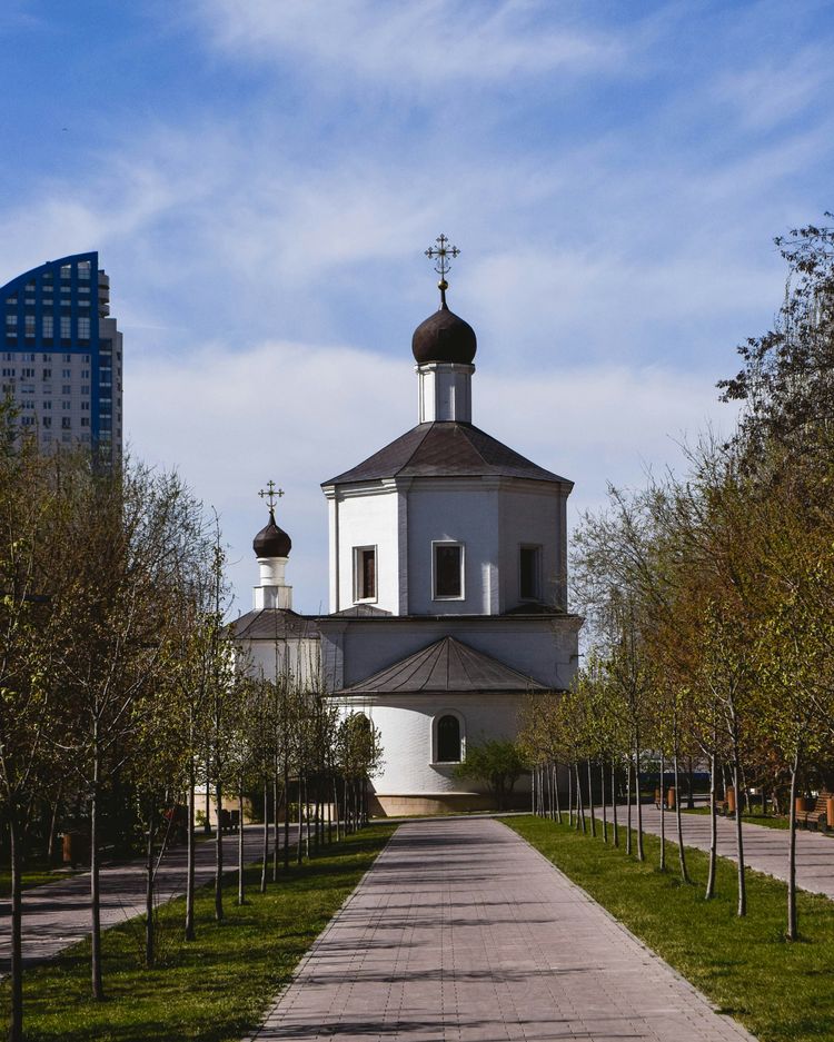 a white church with a steeple surrounded by trees