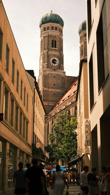 A group of people walking down a street next to tall buildings