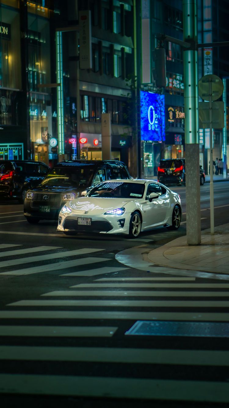 a city street at night with cars driving on it