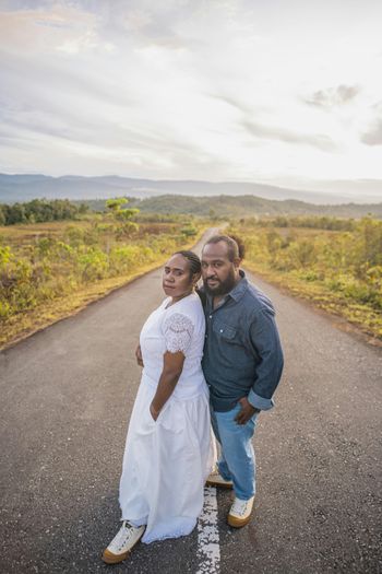 a man and woman posing for a picture on a road