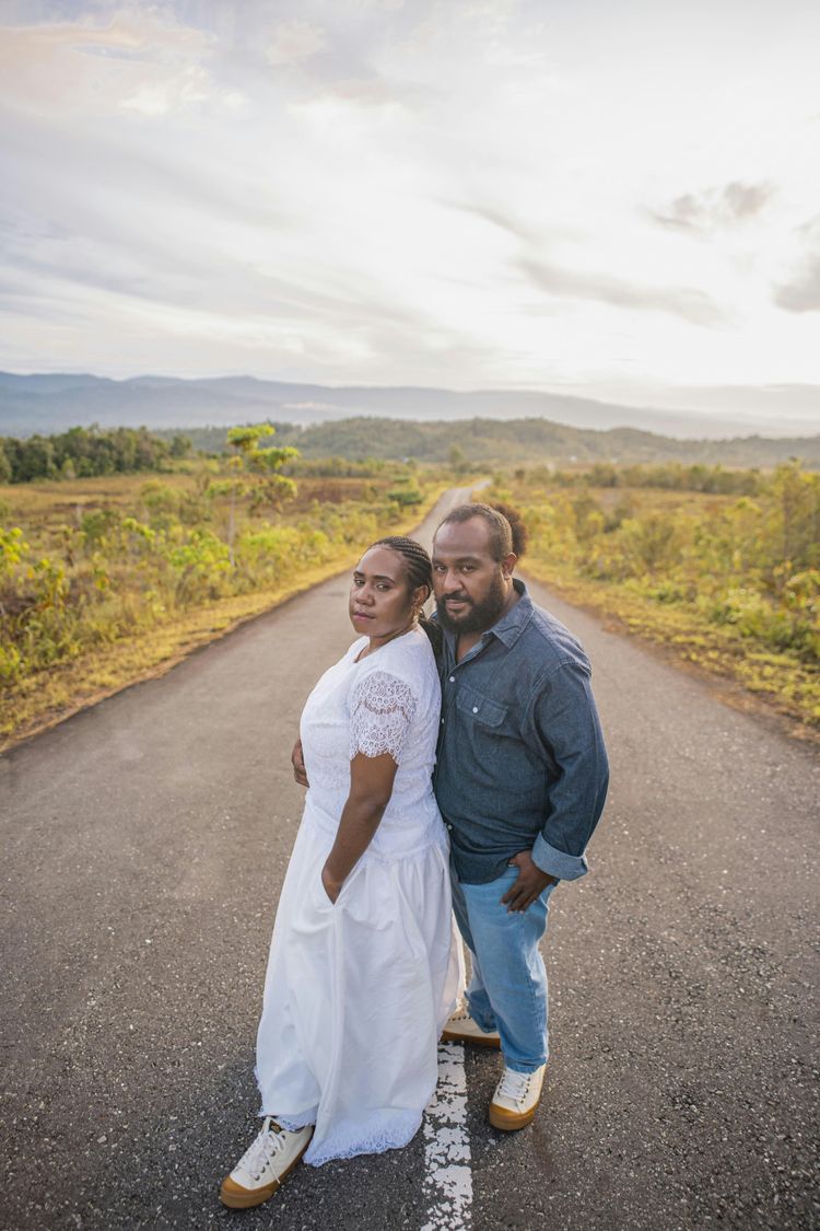 a man and woman posing for a picture on a road