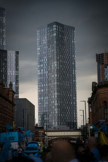 a group of people walking down a street next to tall buildings