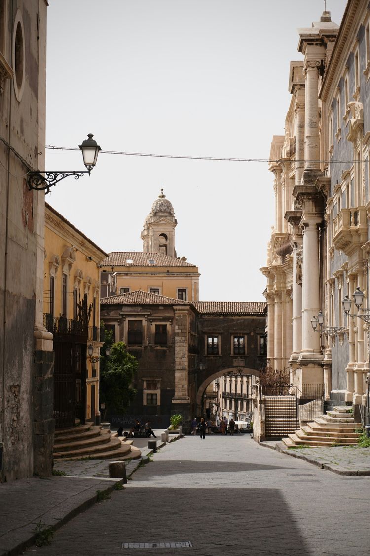 A narrow street lined with tall buildings and a clock tower