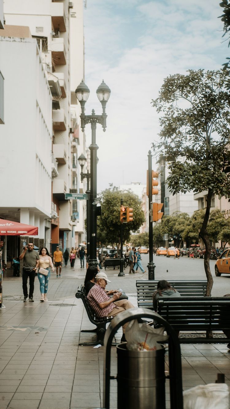 a woman sitting on a bench on a city street