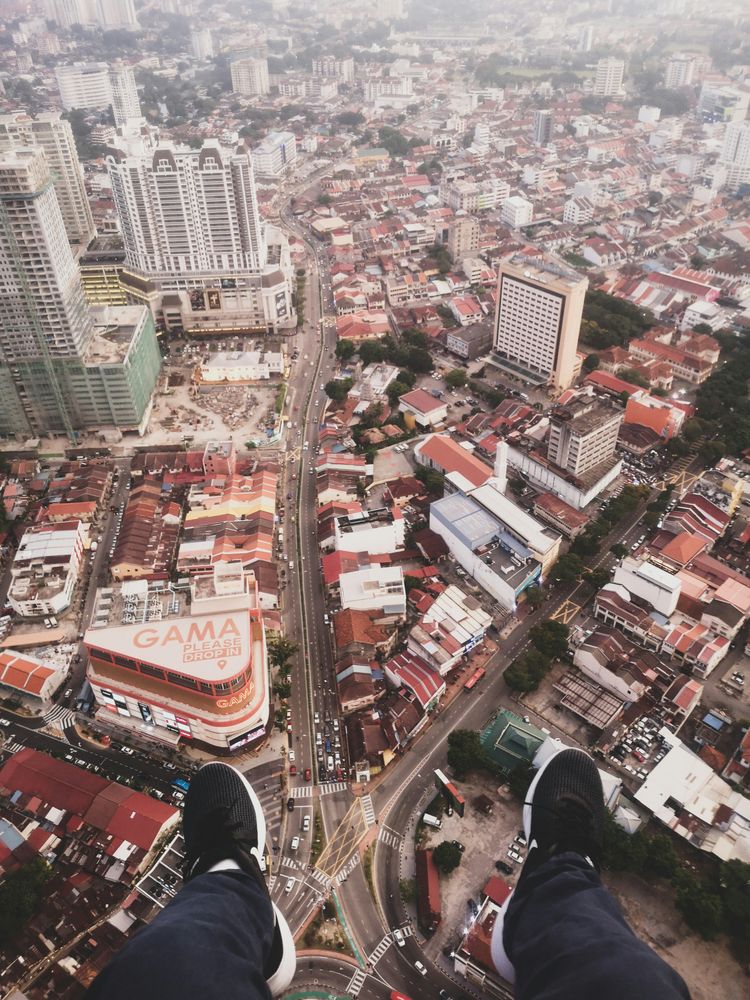 person sitting on building roof edge at the city during day