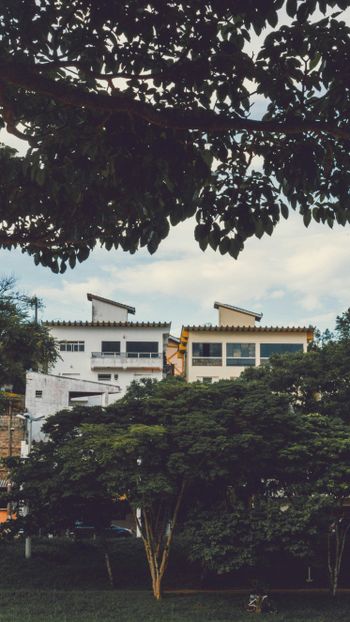 white concrete building near green trees under white clouds during daytime