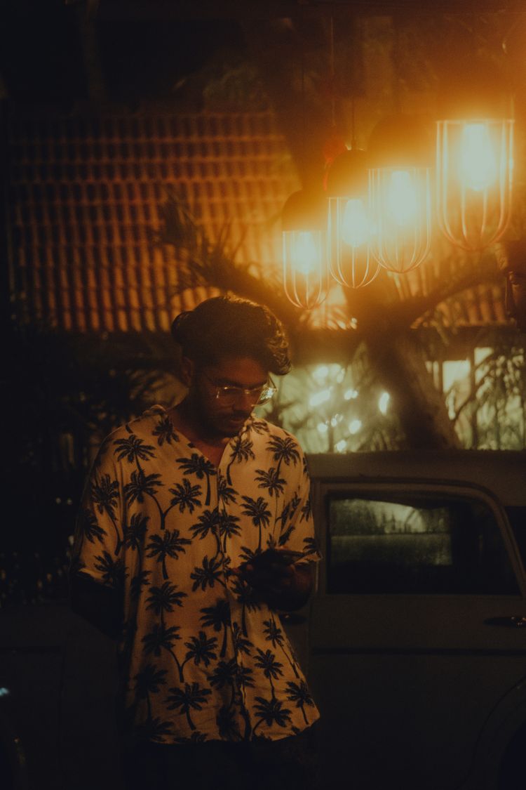 a man standing in front of a car using a cell phone