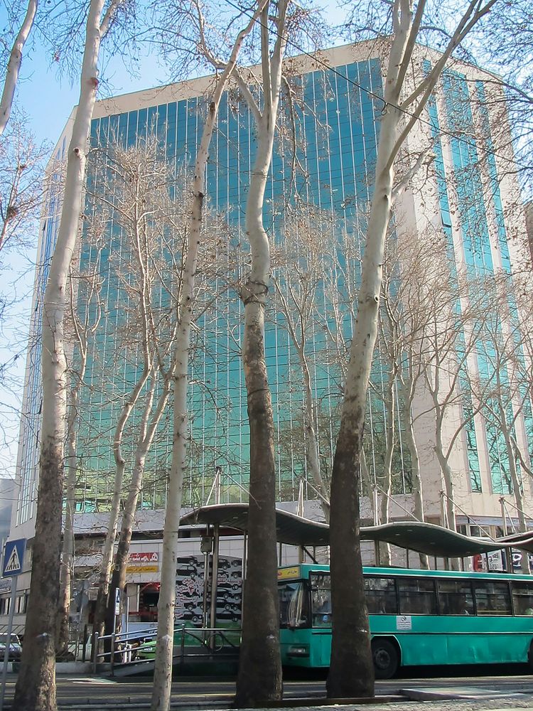 a blue bus parked in front of a tall building