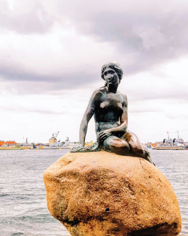 a statue of a woman sitting on top of a rock