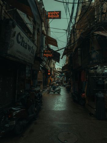 a narrow alleyway with a neon sign above it