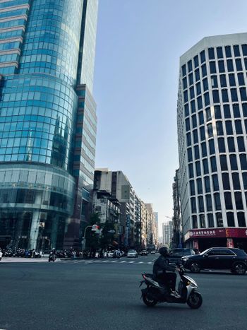 A man riding a motorcycle down a street next to tall buildings