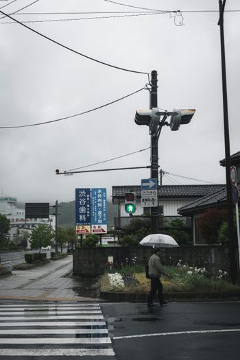 a person walking across a street holding an umbrella