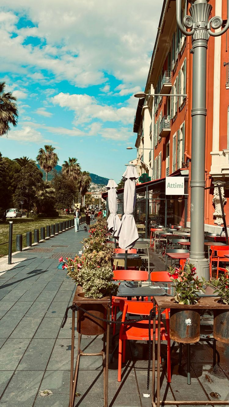 an outdoor cafe with tables and chairs on a sidewalk