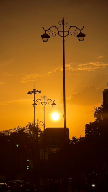 a street light with the sun setting in the background