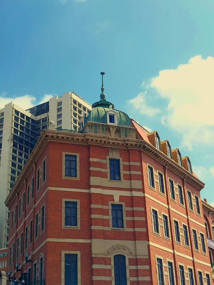 A tall red brick building with a green roof