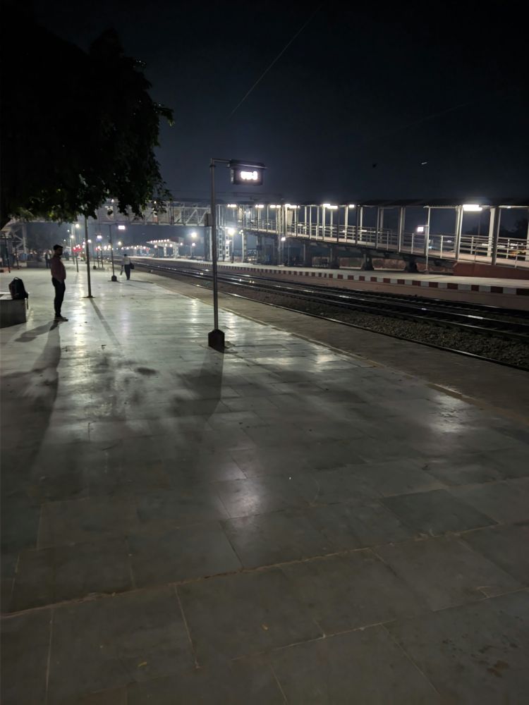 a train station at night with people walking on the platform