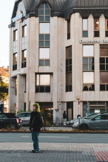 a person standing on a sidewalk in front of a building