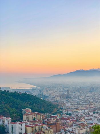 aerial photography of city with high-rise buildings viewing mountain under yellow sky during daytime