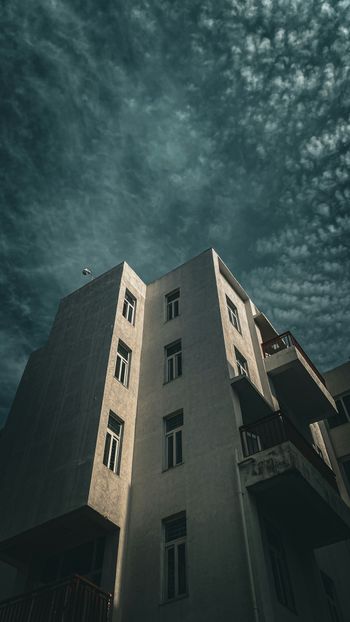 a tall building with balconies against a cloudy sky