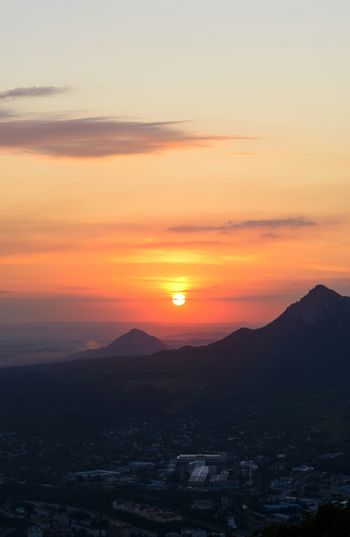 the sun is setting over a city with mountains in the background