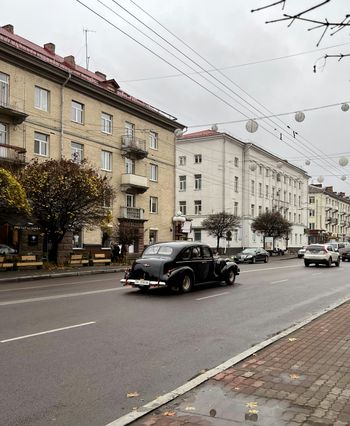 a black car driving down a street next to tall buildings