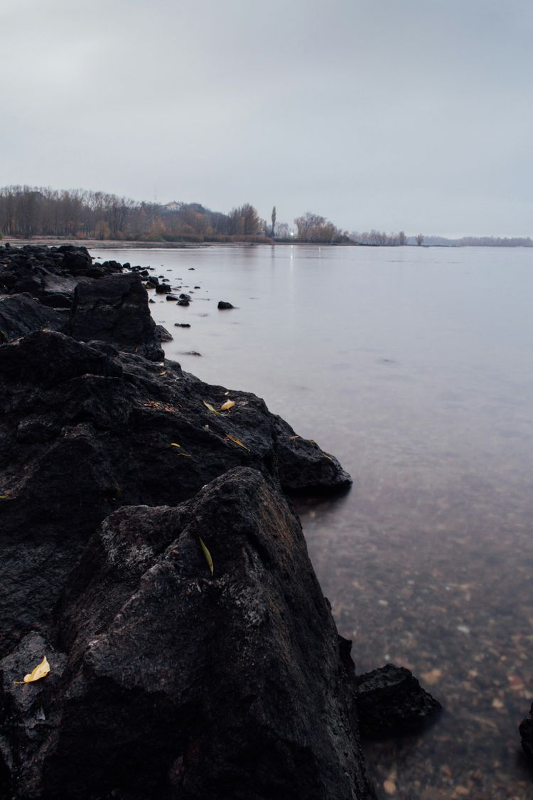 black rock formation on body of water during daytime